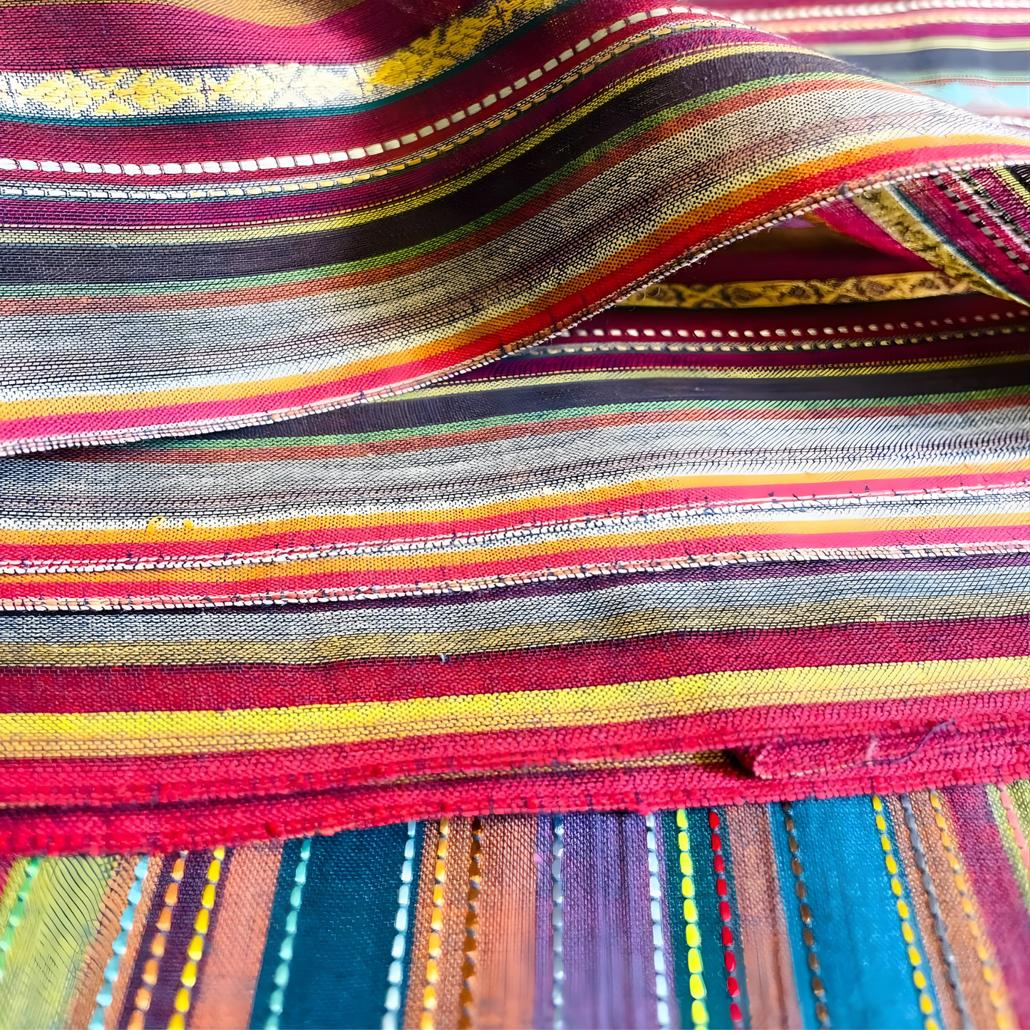 Close-up of woven jacquard material featuring colorful vertical stripes and textured gold accents from Sein Attire.