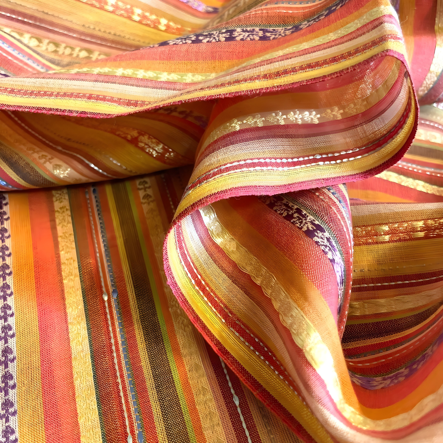 Close-up of woven jacquard fabric featuring colorful stripes and metallic accents suitable for stitched outfits.